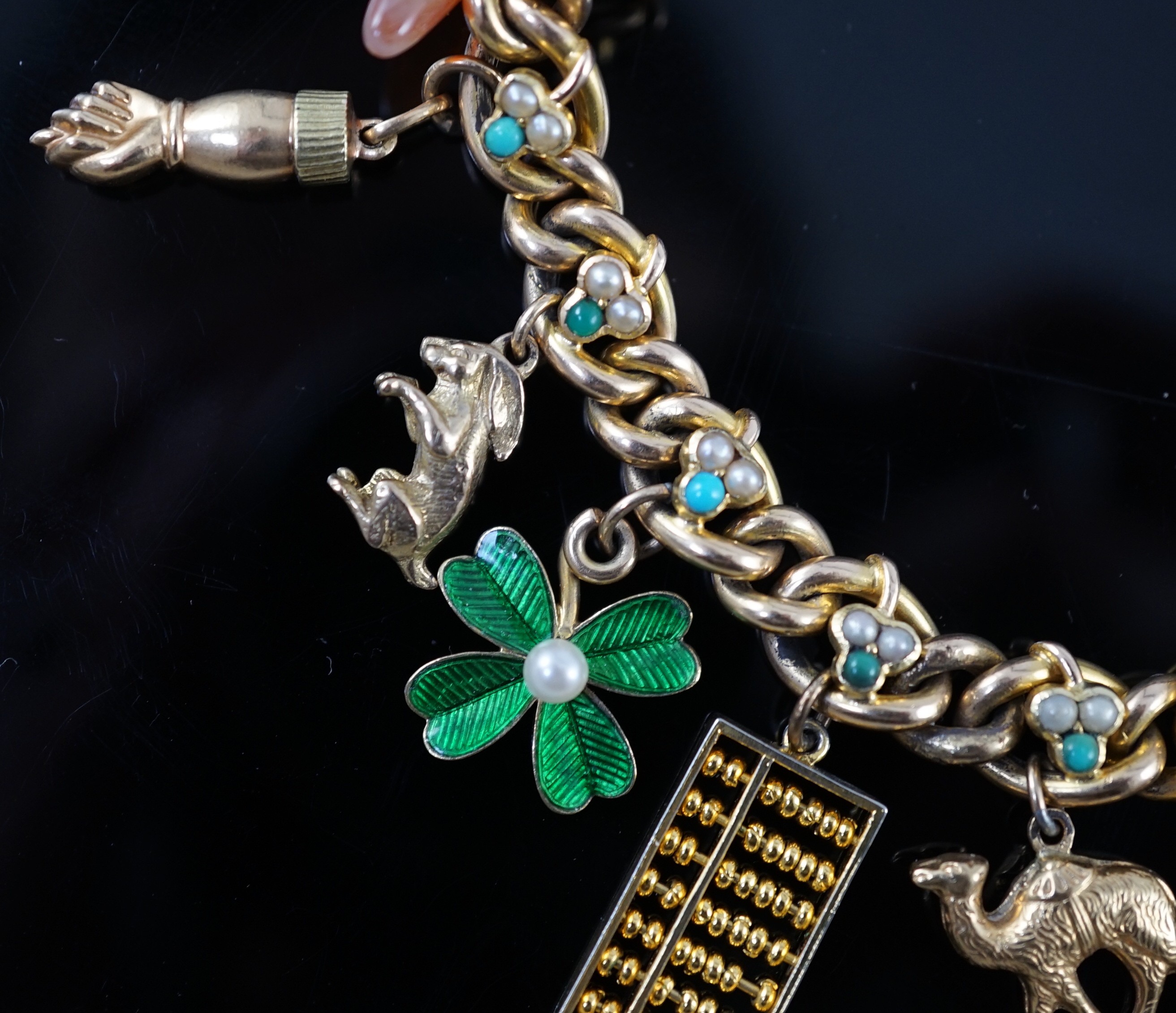 An Edwardian 15ct gold, seed pearl and turquoise set curb link charm bracelet